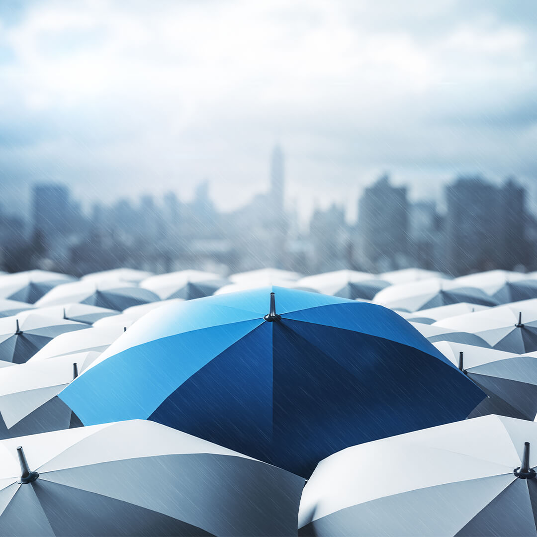 Blue umbrella standing out over many grey umbrellas in the rain with city in the background - Odgers Executive Search Board Headhunters