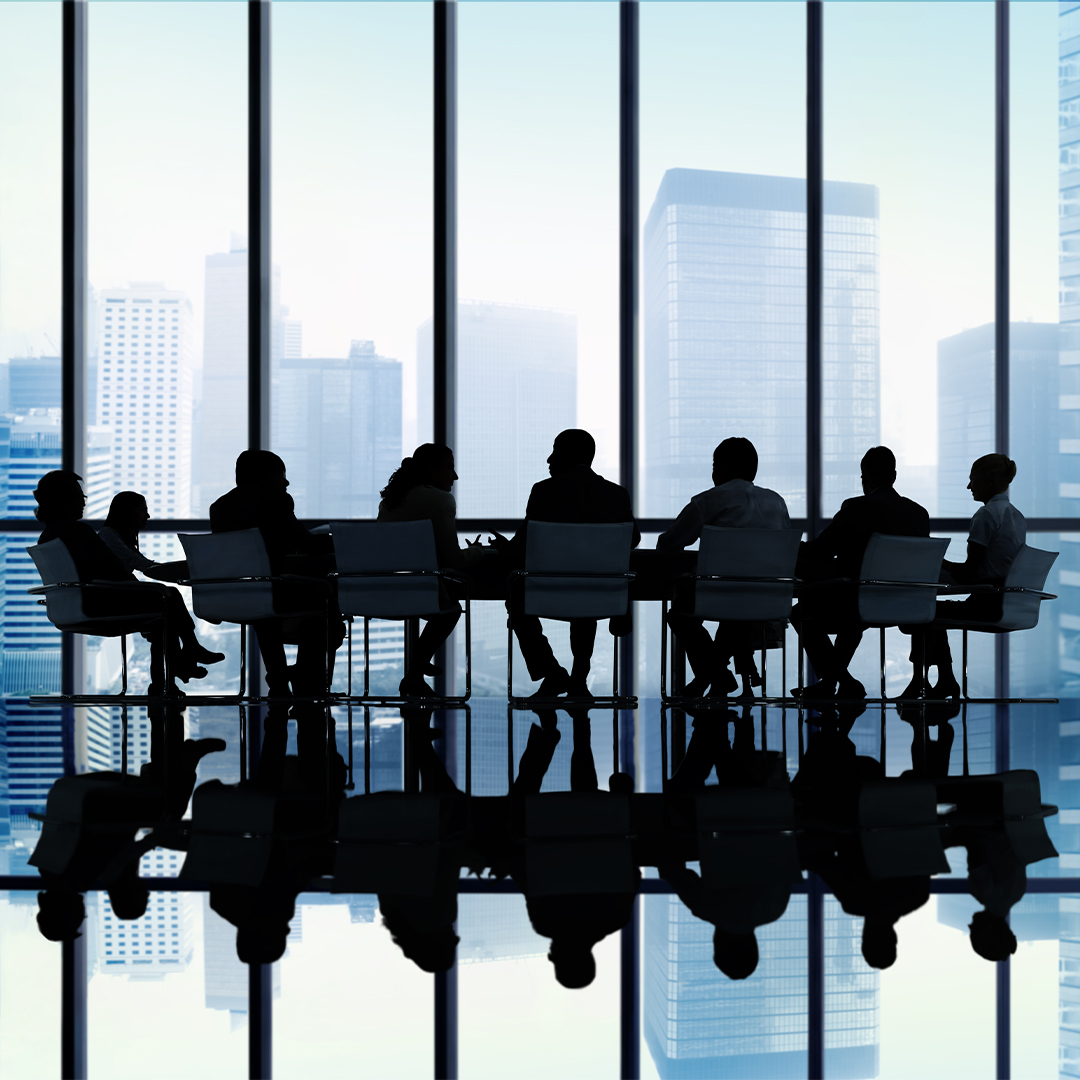 Board members sitting at a board table with a large glass window in the background - Odgers Executive Search Board Headhunters