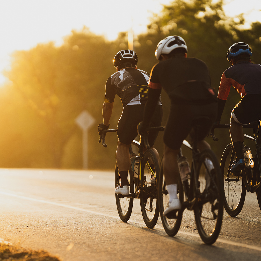 Team of cyclists riding on a road into the sunrise - Odgers Executive Search Board Headhunters