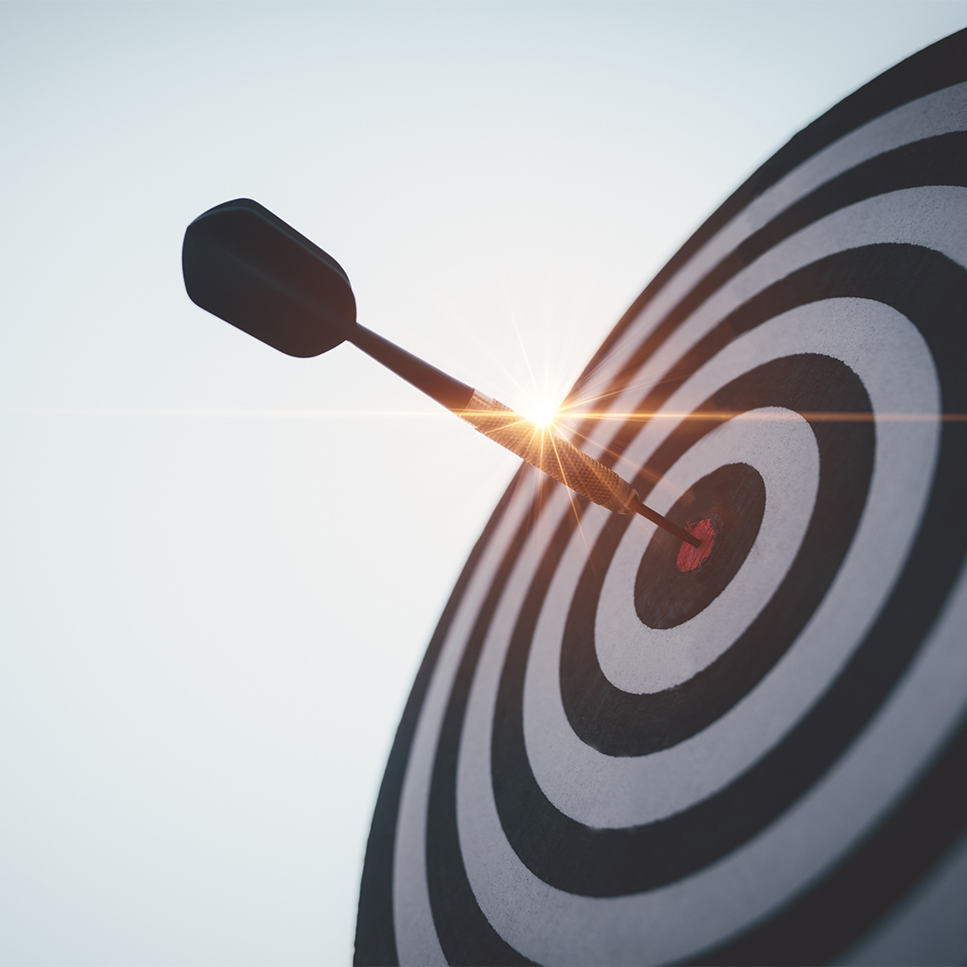 Dartboard with a dart in the bullseye with the sun shining behind - Odgers Executive Search Board Headhunters