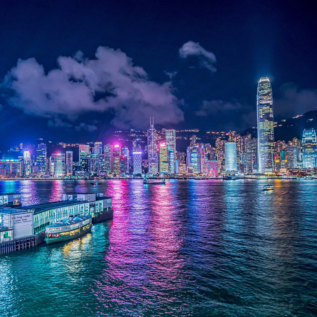 View of bright wharf and vibrant city across the water in the background at night - Odgers Executive Search Board Headhunters