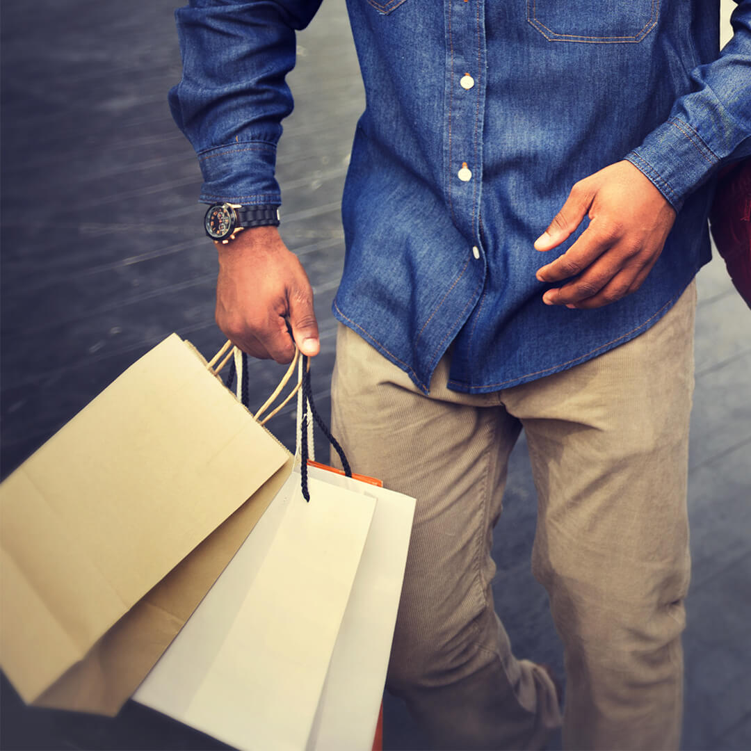 Man in cream pants and blue shirt with black watch carries shopping bags - Odgers Executive Search Board Headhunters